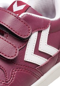 Bordeauxrote Leder-Sneaker mit weißem Zickzackdesign, schwarzem Klettverschluss, kontrastierenden Nähten und einer strukturierten Oberseite für Grip und Unterstützung.