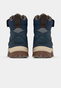 Une paire de bottes de randonnée bleu marine et marron avec des semelles intermédiaires beiges, des languettes visibles et un logo "bisgaard" à l'arrière, vue de l'arrière.