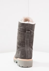 Stivale in suede grigio con una morbida fodera in pelliccia, punta rotonda e suola in gomma testurizzata. Presenta un dettaglio di cucitura lungo la parte posteriore e un'altezza a metà polpaccio.
