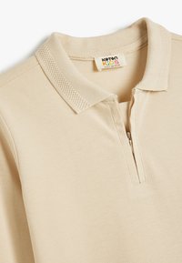 Beige polo shirt met een halve rits, met een gestructureerde kraag en gladde stof. Etiket zegt "Koton Kids."