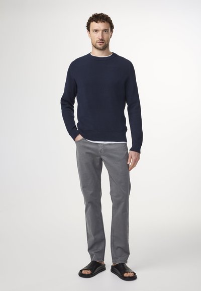 Maglione a costine blu navy, pantaloni grigi a gamba dritta e sandali neri. L'outfit ha un design casual con collo rotondo e una texture sottile.