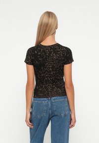 Czarny t-shirt w panterkę z krótkim rękawem, wykonany z miękkiego materiału. Posiada okrągły dekolt i dopasowany krój, pokazany z tyłu.
