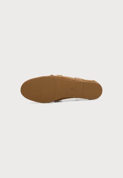 Semelle d'une chaussure marron avec une texture lisse et une légère adhérence, montrant les marquages de la marque et l'étiquette « Made in Spain ».
