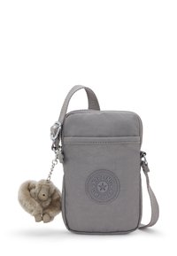 Kleine graue Umhängetasche mit Kipling-Logo auf der Vorderseite und einem flauschigen Affen-Schlüsselanhänger, der an der Seite befestigt ist.