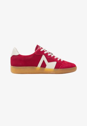 Baskets en daim rouge avec lacets blancs et languette de talon, détail latéral géométrique blanc, et semelle en gomme translucide sur fond blanc.