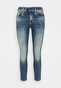 Jeans ajustados en denim oscuro, con un aspecto desgastado, diseño de cinco bolsillos, cierre de botón y un sutil efecto de arrugado en la parte delantera.