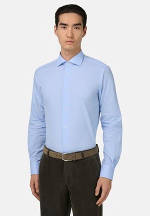 Lichtblauw overhemd met knopen, met een geruit patroon, lange mouwen en een kraag. Gekozen in combinatie met donkere corduroy broek en een bruine riem.