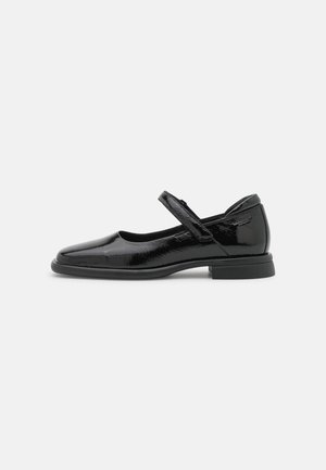 Chaussure Mary Jane en cuir verni noir avec un bout rond, un petit talon et une bride réglable sur le cou-de-pied sur fond blanc.
