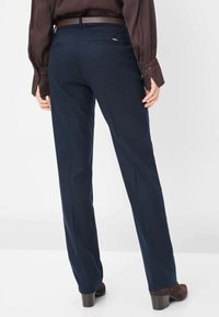 Marineblauwe op maat gemaakte broek met een rechte snit, voorzien van achterzakken en een gladde textuur, gecombineerd met bruin leren haklaarzen.