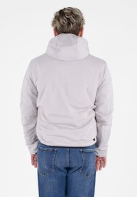 Giacca a cappuccio grigio chiaro con una texture liscia e lucida, polsini elasticizzati e una vestibilità casual, abbinata a jeans in denim blu.
