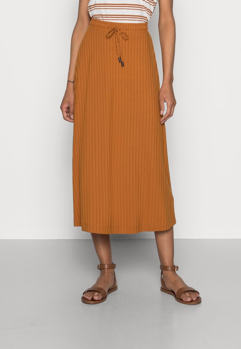 Falda midi de canalé marrón con cintura elástica y cordón. Combinada con sandalias marrones. La superficie es lisa con sutiles líneas verticales.