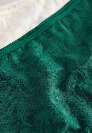 Tissu vert transparent avec un motif de feuilles texturé en bas, agrémenté d'une bande supérieure unie de couleur crème. Les bordures sont soigneusement cousues.