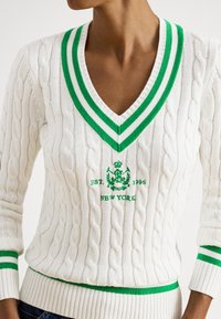 Camisola branca de malha com decote em V às riscas verdes e brancas, apresentando um padrão de trança e bordado com "EST. 1996 NEW YORK" no peito.