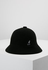 Cappello a secchiello nero realizzato in tessuto testurizzato, con corona arrotondata, visiera ampia e un piccolo logo Kangol sulla parte anteriore.