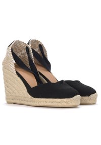 Mustad mustrilahk kootud espadrillid, millel on jute köitest talla, kootud beežist kangast tagumine osa ja mustad kangas rihmad, mis ristuvad pahkluu ümber.
