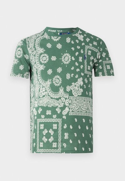 Žalias medvilninis marškinėliai su sudėtingais baltais paisley ir gėlių raštais, apvaliu kaklu ir trumpomis rankovėmis.