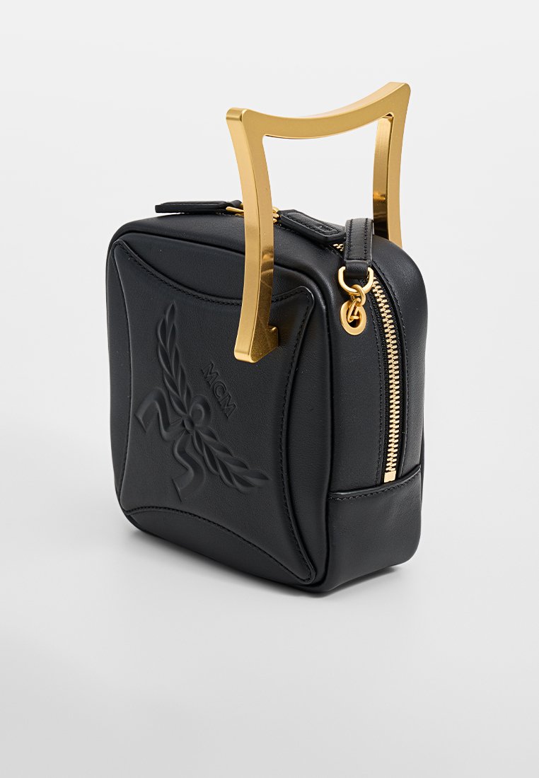 Schwarze Lederhandtasche mit einem goldenen Metallgriff, quadratischer Form, geprägtem Logo-Detail und einem Reißverschluss auf einer Seite.