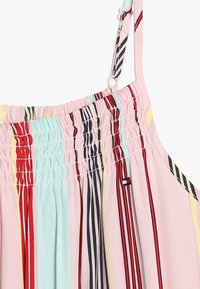 Mnohobarvá bezramínková blůza se svislými pruhy v červené, černé a pastelových odstínech, s shromážděnou texturou a tenkými nastavitelnými ramínky.