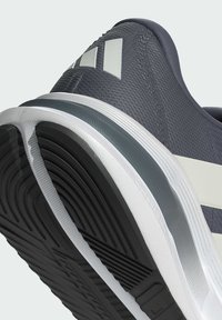 Gray athletic shoe featuring a textured upper, white accents, and a split rubber sole with a visible tread pattern and cushioning detail.