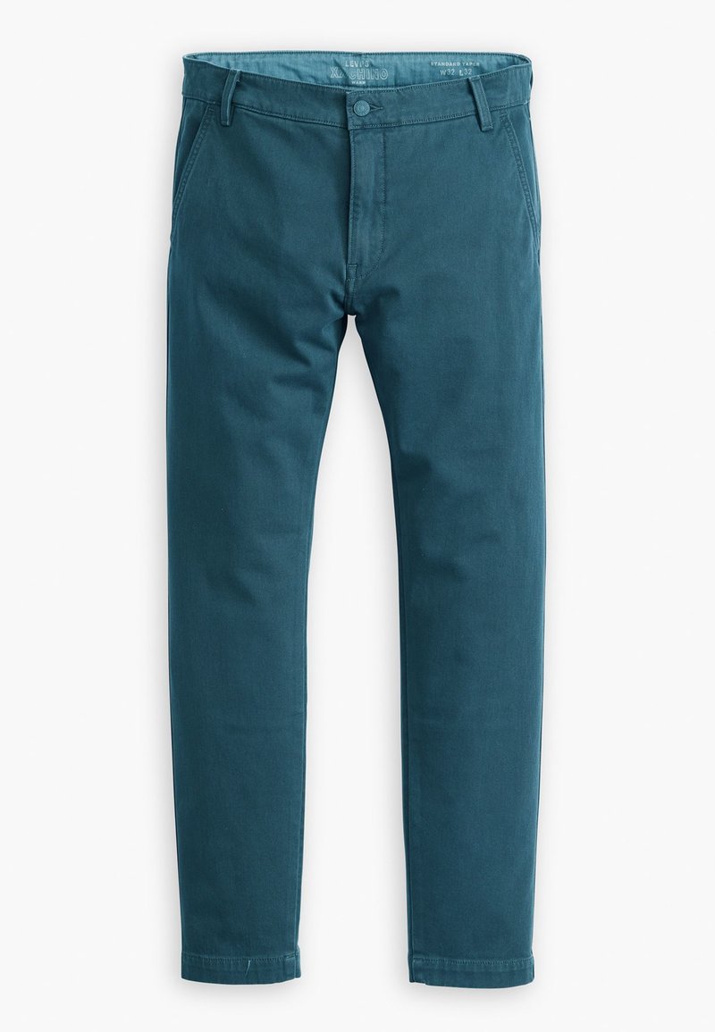Chinos teal en mélange de coton, avec un devant plat, deux poches latérales et un design de jambe légèrement fuselée. Fermeture à bouton standard à la taille.
