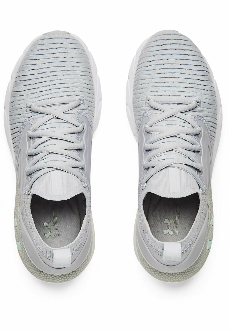 Zapatillas deportivas grises con un upper texturizado, punta redonda y cordones elásticos. Presentan una suela acolchada y una marca en el talón y la lengüeta.