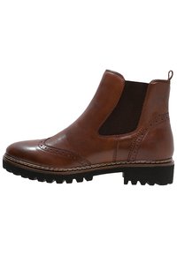 Bottines Chelsea en cuir brun avec panneaux latéraux élastiques, détails en brogue et semelle en caoutchouc noir épaisse. Texture lisse avec des accents de couture.