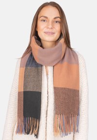 Écharpe en tartan dans les teintes d'orange, de marron et de noir, fabriquée en tissu doux avec des bords à franges, enroulée autour du cou.