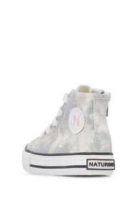 Sneakers alte argento con una parte superiore metallica texturizzata, lacci bianchi, un patch logo rosa e una suola a righe bianco e nera.