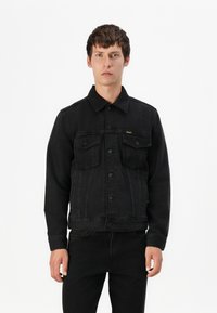 Black denim jacket with a button-up front, two chest pockets, and a pointed collar. Features a slightly fitted shape and textured fabric.