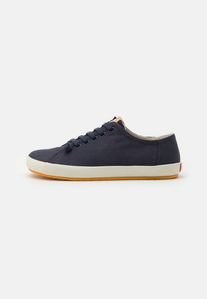 Zapatillas de lona navy con puntera redonda, cuello beige, entresuela blanca y suela de goma naranja. Cuenta con seis ojetes y cordones planos.