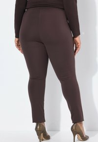 Bruna stretchleggings med smal passform, ankellängd, som är kombinerade med texturerade metalliska klackskor. Slätt tyg, minimal detaljering.
