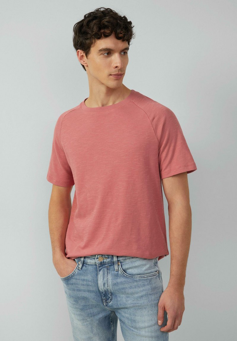 T-shirt z krótkim rękawem, okrągłym dekoltem w jasnoróżowym, fakturowanym materiale. Lu�źny krój z rękawami raglanowymi, zestawiony z jasnoniebieskimi dżinsami.