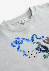 Lichtgrijze sweatshirt met een blauwe lintgrafiek waarop "hoop & hart" staat en een geïllustreerde wasbeer die een tak vasthoudt.