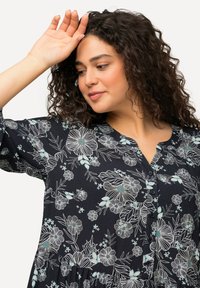 Blumenkleid mit dunkelblauem Hintergrund, das weiße und hellblaue Blumenmuster aufweist, kurze Ärmel, Knopfleiste und einen lockeren Schnitt hat.