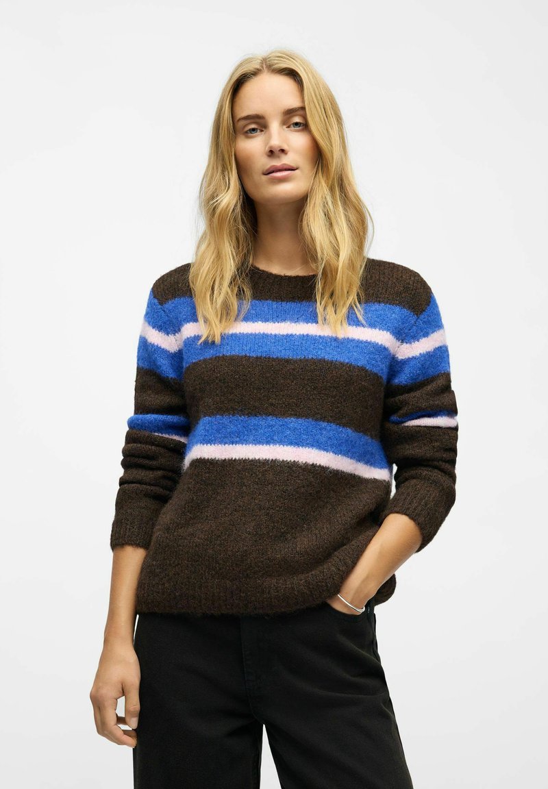 Brown striped sweater with blue, pink, and white horizontal lines. Soft texture, crew neckline, and relaxed fit. Paired with black pants.