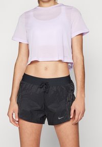 Laventelivärinen verkkotoppi, jossa on pyöreä kaula-aukko ja lyhyet hihat, yhdistettynä mustiin kevyisiin shortseihin, joissa on nyöri ja sivuviivat.