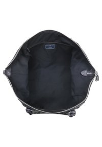 Czarna torba z zamkiem błyskawicznym, wnętrze w jednolitym czarnym kolorze, z metką i minimalnym okuciem. Okrągły kształt o miękkiej teksturze.