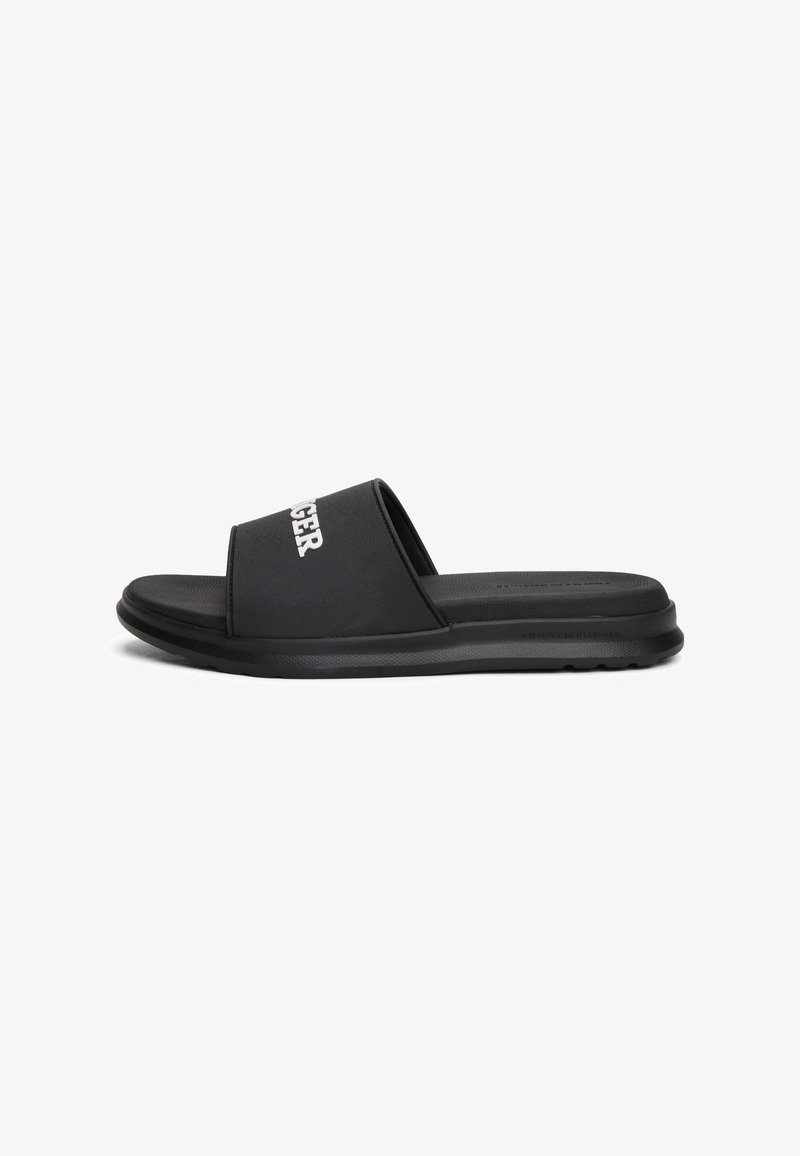 Sandale slide noire avec une semelle épaisse et une large sangle sur le dessus avec un texte blanc.