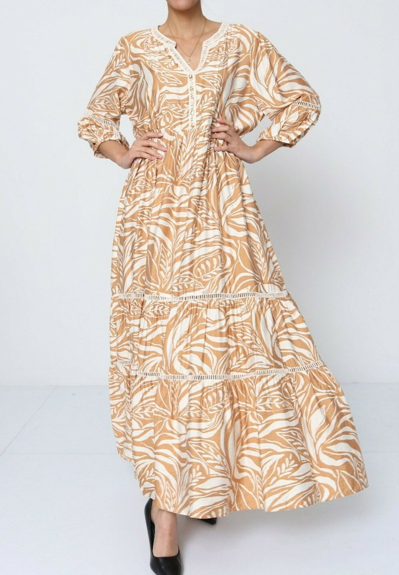 Robe maxi beige avec imprimé botanique blanc, dotée d'un décolleté en V, de détails en boutons et d'une jupe à volants. Tissu doux avec des manches ballon.