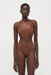 Brown one-piece swimsuit with a square neckline, cut-out sides, textured fabric, and thick straps. Designed for a fitted silhouette.