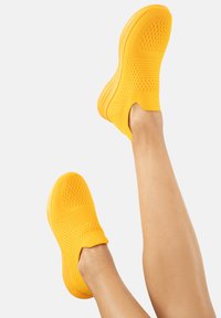 Gelbe Slip-On-Sneaker mit einem strukturierten Strick-Obermaterial, runder Zehenform und einer gepolsterten Sohle für Komfort und Flexibilität.