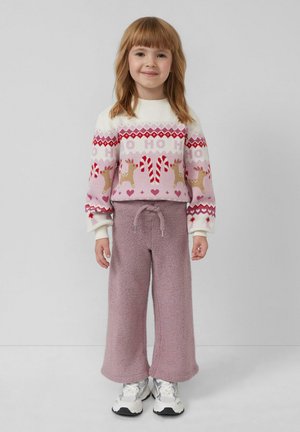 Helles rosa festliches Sweatshirt mit Rentieren und Zuckerstangen, kombiniert mit flauschigen, lockeren lavendelfarbenen Hosen und weißen Sneakers.