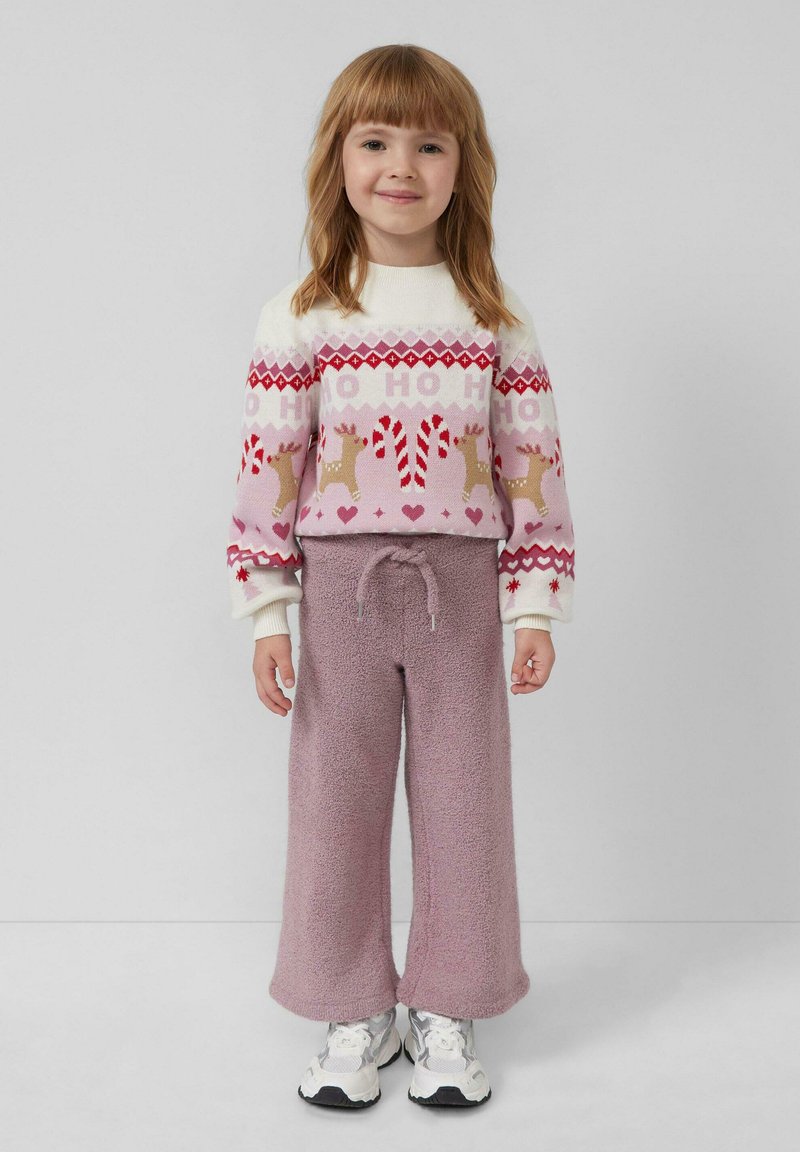 Helles rosa festliches Sweatshirt mit Rentieren und Zuckerstangen, kombiniert mit flauschigen, lockeren lavendelfarbenen Hosen und weißen Sneakers.