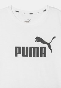 Camiseta de algodón blanca con un estampado negro de "PUMA" y un logo de un puma saltando. Cuello redondo con un sutil logo en el cuello.