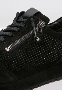 Baskets en suède noir avec une surface texturée et des accents cloutés, un détail zippé sur le côté et des lacets noirs. Semelle en caoutchouc incluse.
