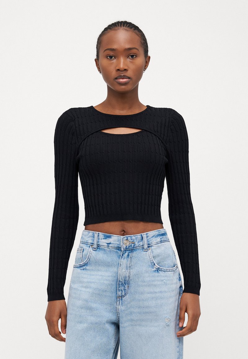 Must mustriba crop-top pikendatud varrukatega, mille kaeluses on auk. Kombineeritud helesiniste kõrge vöökohaga teksadega.