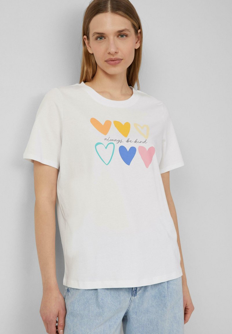 T-shirt en coton blanc présentant un graphique de cœurs colorés en orange, jaune, turquoise, bleu, rose, avec le texte "sois toujours gentil."