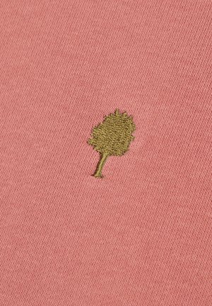 Piccolo albero ricamato di colore verde oliva su sfondo di tessuto rosa testurizzato.