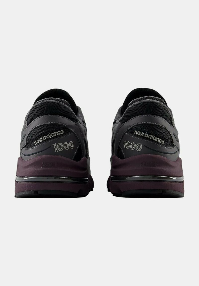 Des chaussures de sport noires et grises avec une semelle intermédiaire violette proéminente, un dessus en maille et synthétique, offrant un soutien rembourré avec le logo "New Balance 1000".