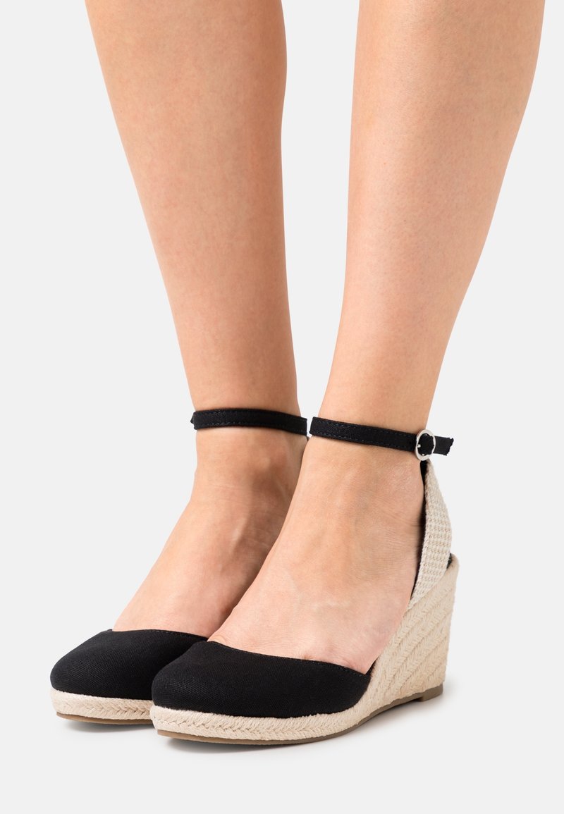 Scarpe con tacco a cuneo in tessuto nero con tacco in beige intrecciato e cinturino alla caviglia con dettaglio in fibbia argentata.